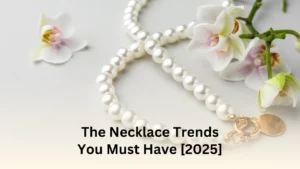 A pearl necklace with a gold clasp, elegantly displayed next to white orchid flowers on a light background. Text overlay reads 'The Necklace Trends You Must Have [2025]